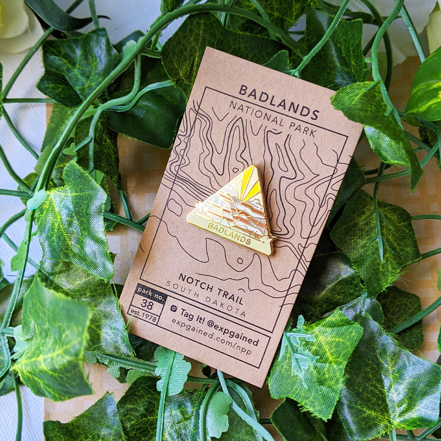 Triangle Badlands national park enamel pin featuring a view from the beehive hike on a brown business card size backing card with a topo map of the popular Notch Trail.