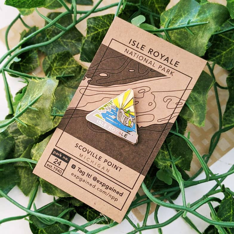 Triangle Isle Royale national park enamel pin featuring a view from the beehive hike on a brown business card size backing card with a topo map of Scoville Point.