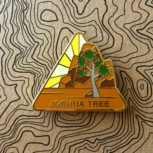 Triangle Joshua Tree national park enamel pin featuring a view of the rocky landscape and joshua tree.