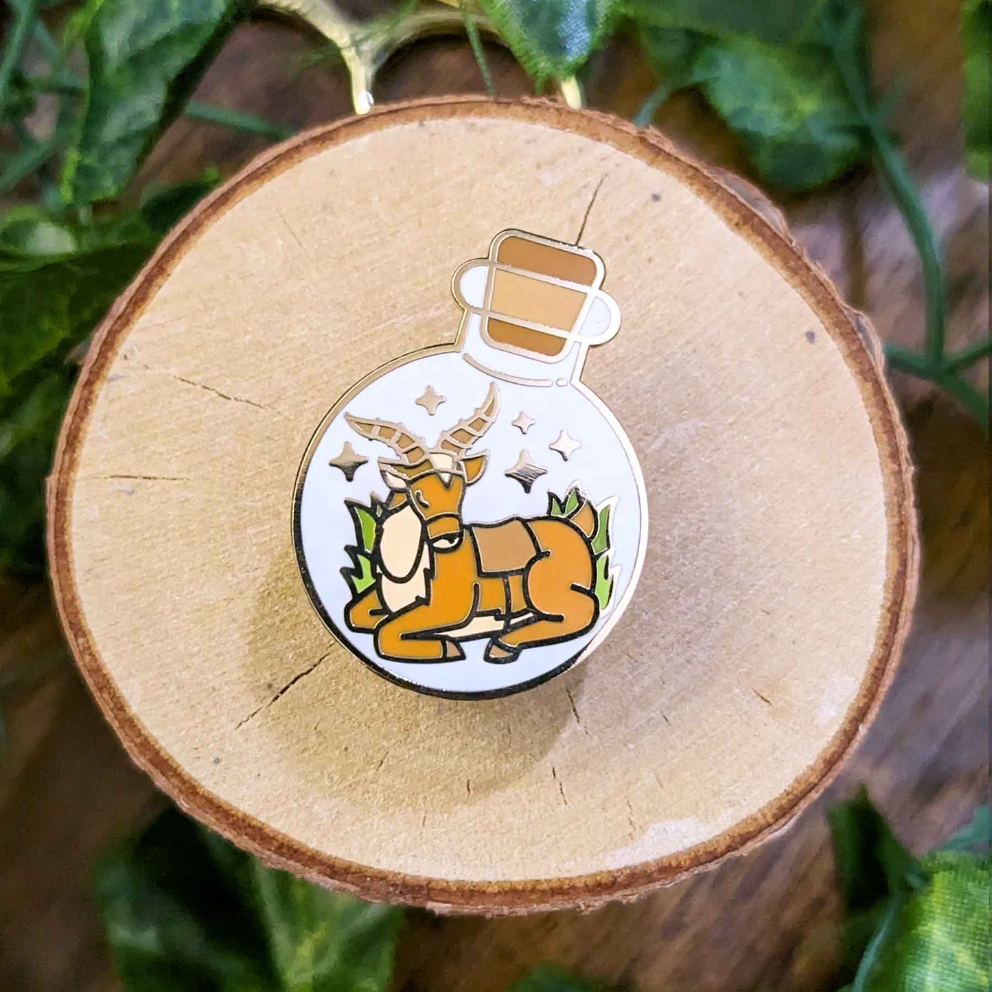 Resting brown antelope deer with saddle in a potion bottle enamel pin designed by EXP Gained