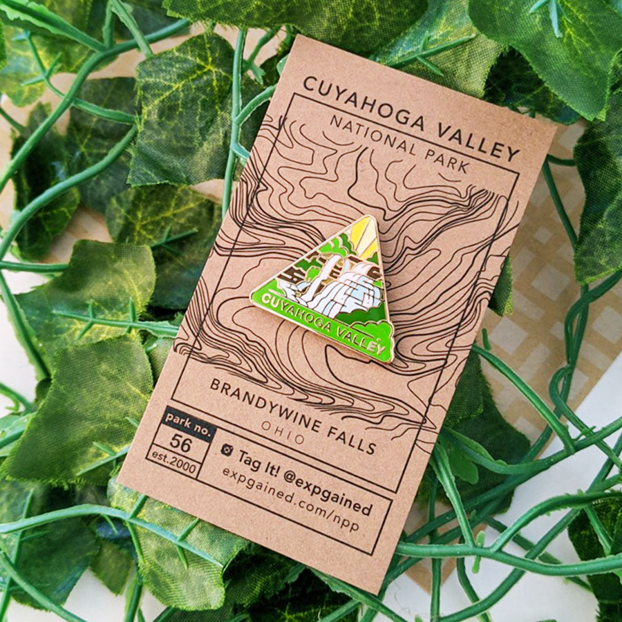 Triangle Cuyahoga Valley national park enamel pin featuring a view from the beehive hike on a brown business card size backing card with a topo map of the Brandywine Falls location.