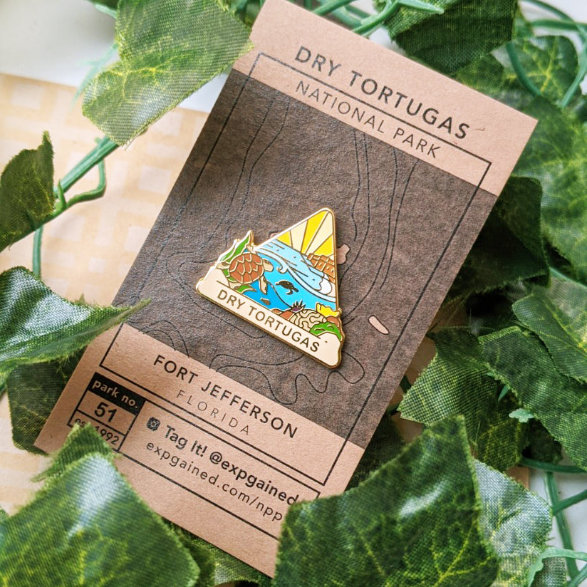 Triangle Dry Tortugas national park enamel pin featuring a view from the beehive hike on a brown business card size backing card with a topo map of the Fort Jefferson area.