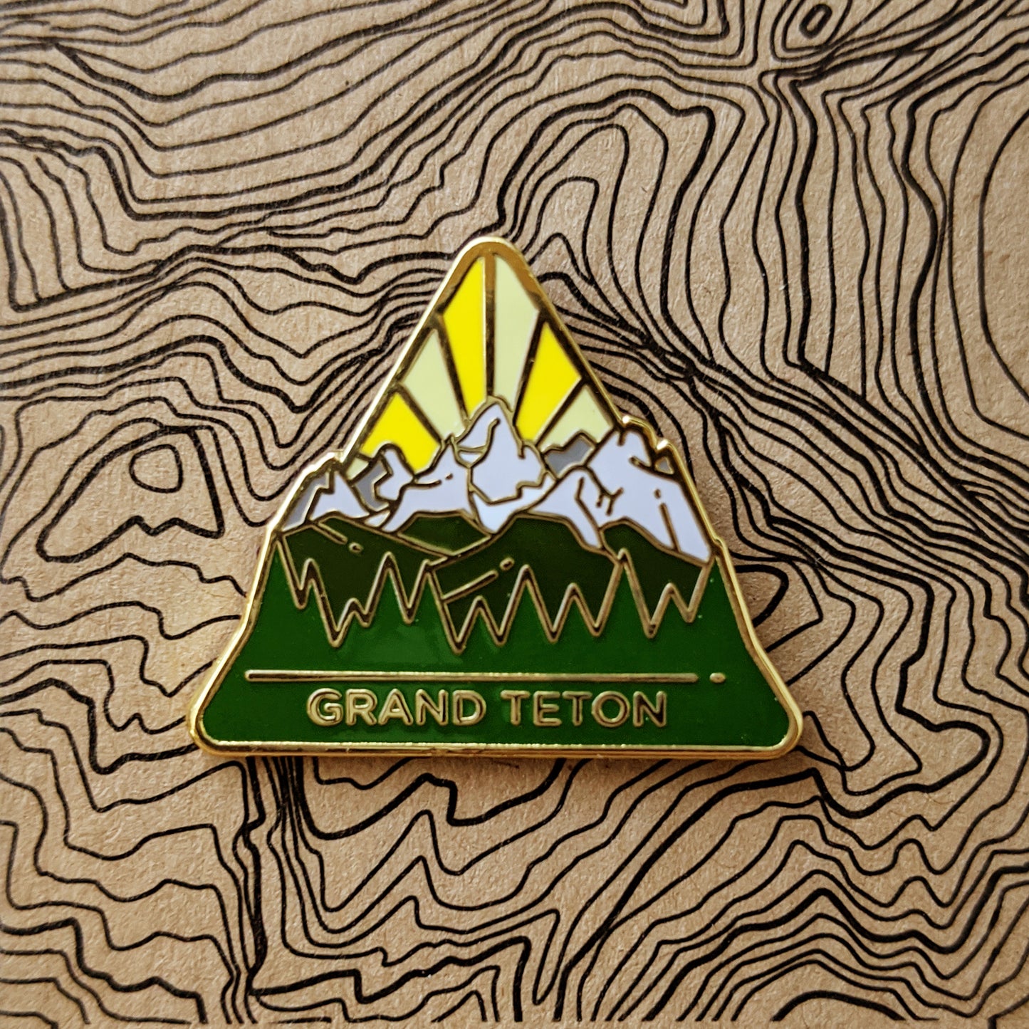 Triangle Grand Teton national park enamel pin featuring a view of the teton range.