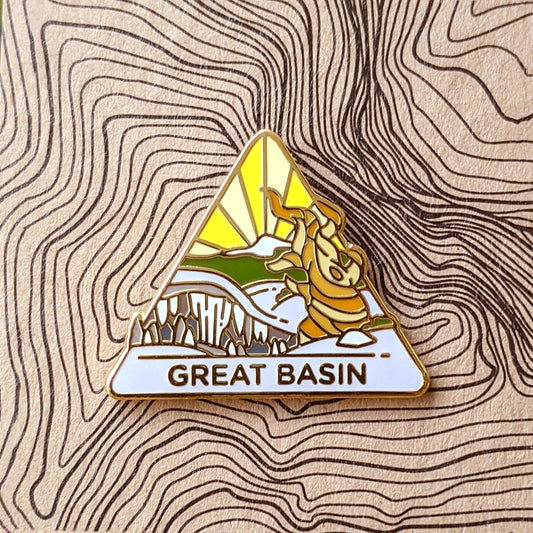 Triangle Great Basin national park enamel pin featuring a view of wheeler peak, caves, and a bristlecone tree.