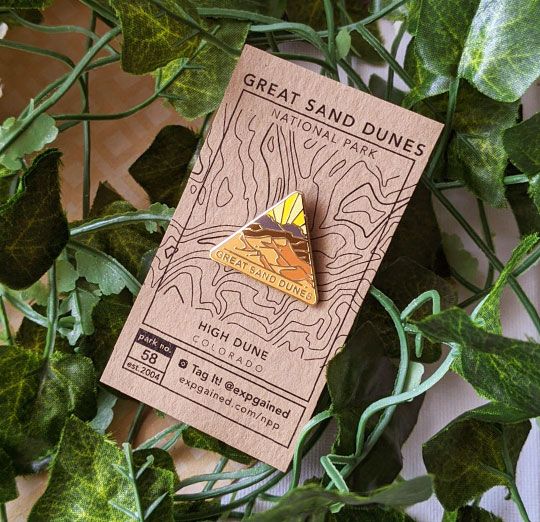 Triangle Great Sand Dunes national park enamel pin featuring a view from the beehive hike on a brown business card size backing card with a topo map of High Dune.