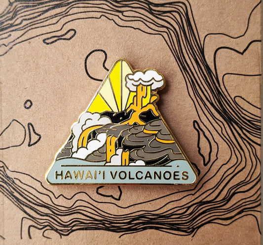Triangle Hawai'i Volcanoes national park enamel pin featuring a view of a volcanic eruption flowing into the ocean.