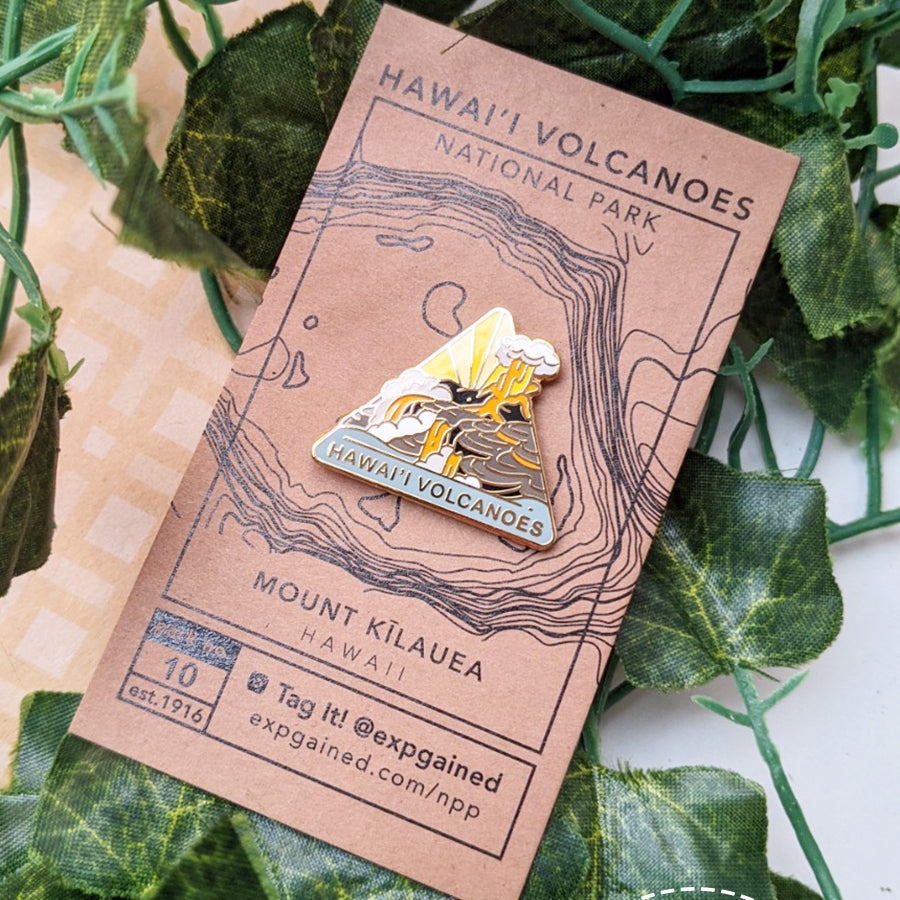 Triangle Hawai'i Volcanoes national park enamel pin featuring a view from the beehive hike on a brown business card size backing card with a topo map of the Mount Kilauea.