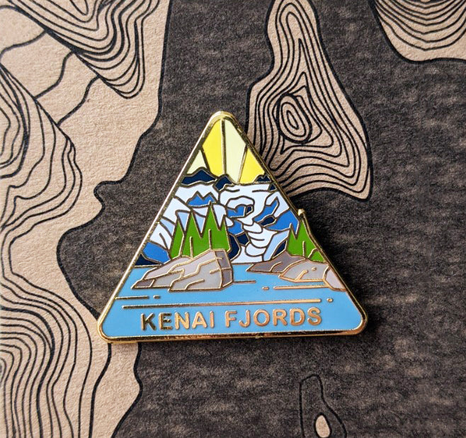 Triangle Kenai Fjords national park enamel pin featuring a view of a northwestern fjord created by the Harding Icefield.